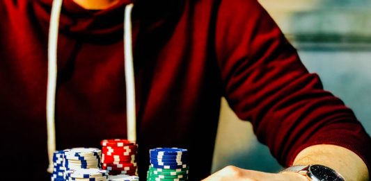 Mind games: how to train Poker Brain person holding playing cards beside poker chips