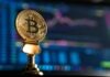 What is Backing Bitcoin? selective focus photo of Bitcoin near monitor