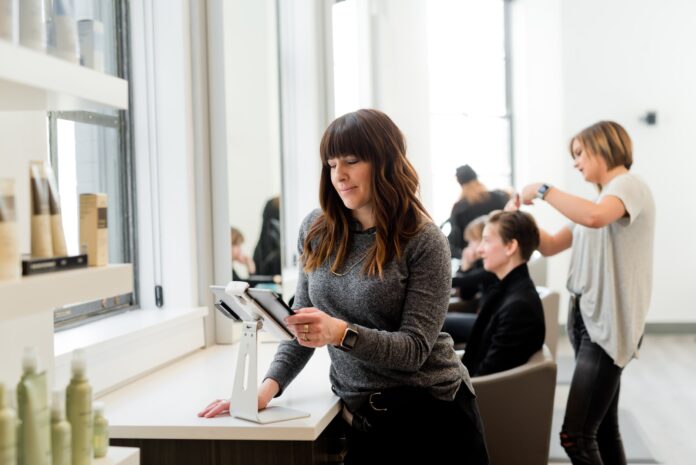 Photo by Adam Winger woman in gray sweater holding tablet computer