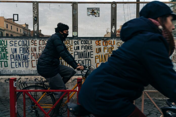 Photo by Gabriella Clare Marino man in black jacket riding red bicycle