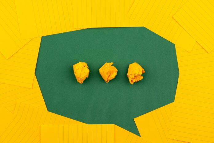 Photo by Volodymyr Hryshchenko three crumpled yellow papers on green surface surrounded by yellow lined papers