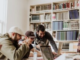 5 Reasons Why You Should Help Your Fellow Students Get Better three men laughing while looking in the laptop inside room