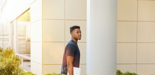 Six Basic Reasons Why College Students Become Unemployed man holding laptop walking towards building