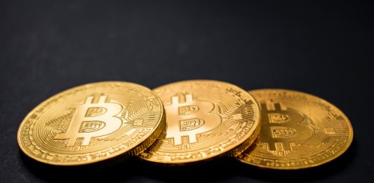 Bitcoin Prime the Automated Software three gold-colored bitcoins on black surface