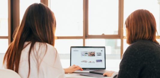 10 Key Steps To Building A Great Small Business Website two women talking while looking at laptop computer