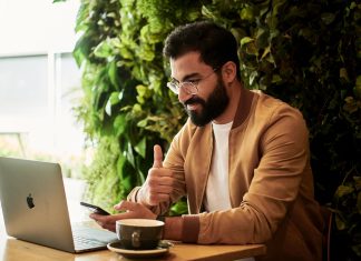 Tips to Organize Your Small Business man in brown jacket sitting at a table looking at laptop