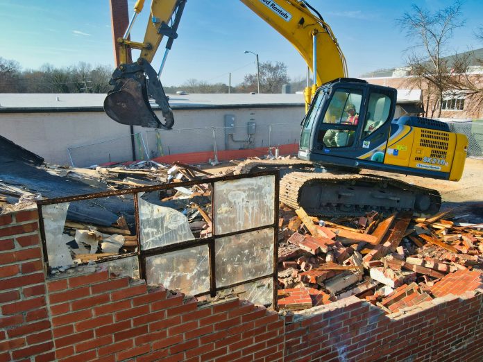Photo by Gene Gallin yellow and black excavator on brown brick wall during daytime