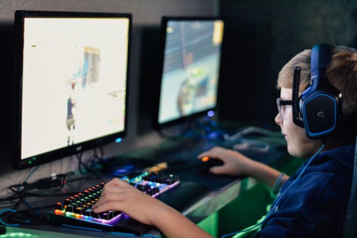 Photo by Alex Haney boy wearing headset playing computer game