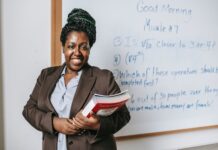 Five Alternative But Lucrative Careers In Education You Should Look Into Free Cheerful black female teacher with workbooks standing near whiteboard Stock Photo