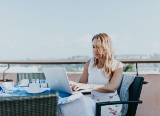How the Digital Nomad Lifestyle Can Help You Break the 9 To 5 Routine woman sitting on chair while using MacBook