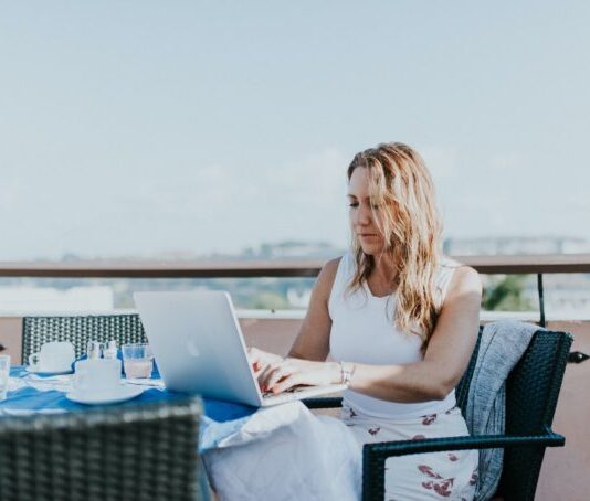 How the Digital Nomad Lifestyle Can Help You Break the 9 To 5 Routine woman sitting on chair while using MacBook