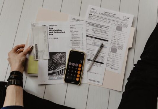 Can’t Afford to Pay Back Taxes? Here Are Your Options person holding paper near pen and calculator