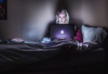 How to Avoid Scams By Reading Reviews First woman sitting on bed with MacBook on lap