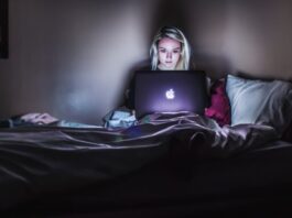 How to Avoid Scams By Reading Reviews First woman sitting on bed with MacBook on lap