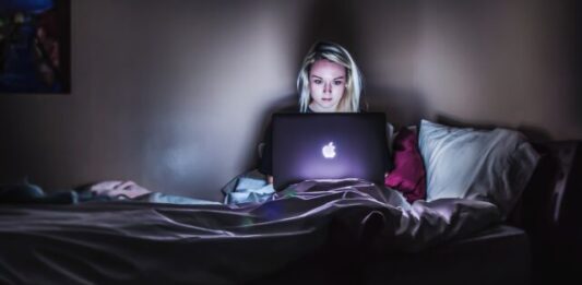 How to Avoid Scams By Reading Reviews First woman sitting on bed with MacBook on lap