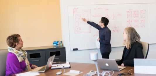 Why Traditional Quality Assurance is Giving Way to QA-as-a-Service man in black dress shirt writing on dry-erase board