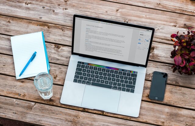 Photo by Bram Naus silver MacBook beside space gray iPhone 6 and clear drinking glass on brown wooden top