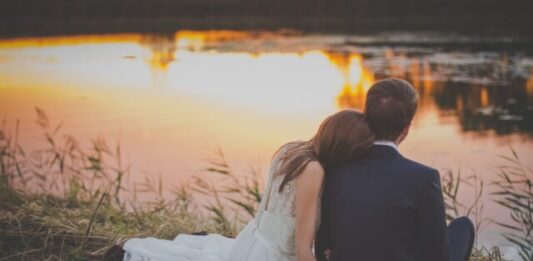 New Study Reveals the Top Traits Most Desired in a Romantic Partner sitting woman leaning on man's shoulder facing lake during golden hour