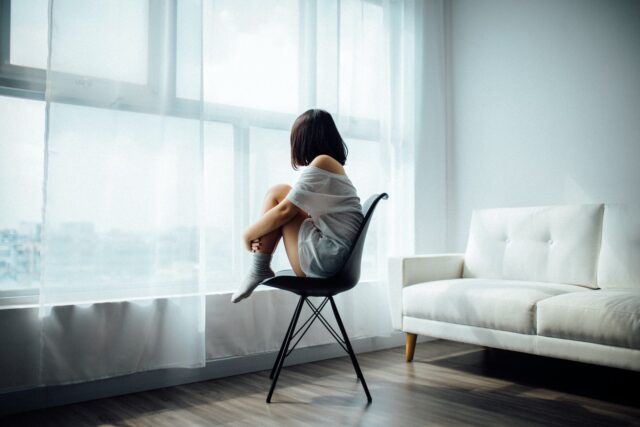 Photo by Anthony Tran woman sitting on black chair in front of glass-panel window with white curtains
