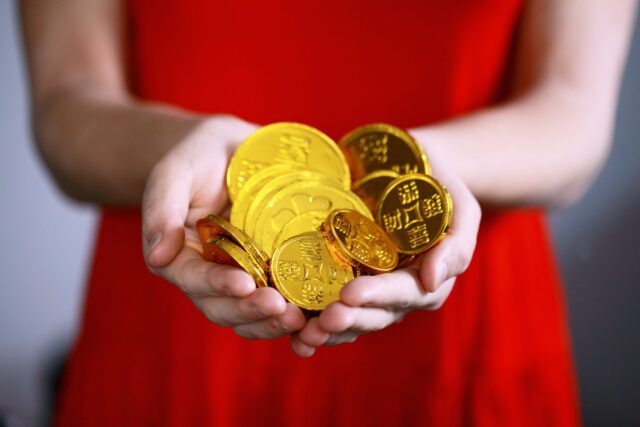 Photo by Alexander Grey person holding gold-colored ching coins