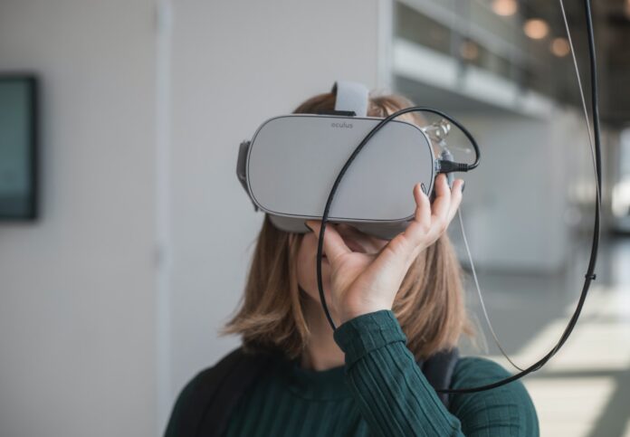 Photo by Maxim Hopman woman in black sweater holding white and black vr goggles