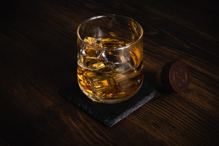 Photo by Timothy James a glass of whiskey sitting on top of a wooden table