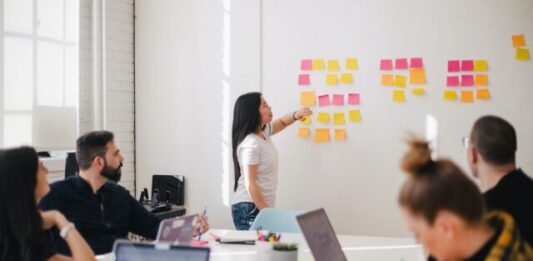 The Business Benefits of E-learning Software: From Onboarding to Professional Development woman placing sticky notes on wall