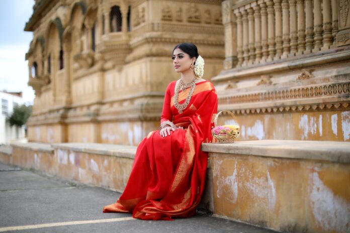 Photo by inesh thamotharampillai woman in red long sleeve dress sitting on gray concrete bench during daytime