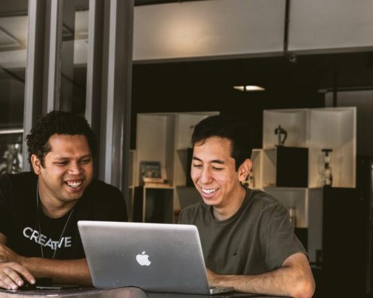 Key Factors to Consider When Choosing the Best Workers’ Compensation Insurance Provider two smiling men looking at MacBook