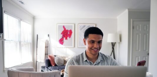 11 Easy Ways to Make Money in the Digital Age man in gray hoodie sitting on chair in front of silver macbook