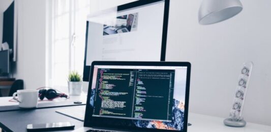 Strategic Synergy: Integrating Composable Commerce into Your SAP Tech Stack for Market Agility A MacBook with lines of code on its screen on a busy desk