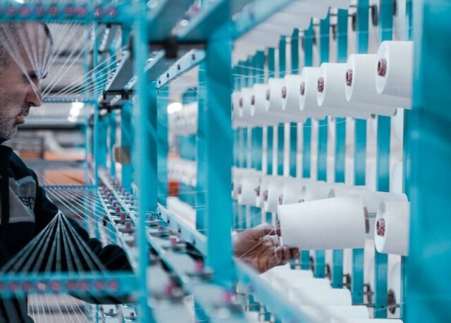 Photo by Oğuzhan KARACA Man in Black Jacket Standing Beside Blue Metal Machine