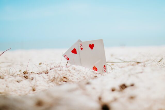 Photo by Muaz AJ white and red heart playing card on white sand during daytime