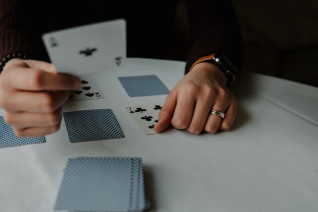 Photo by Andrik Langfield person holding playing cards on white table