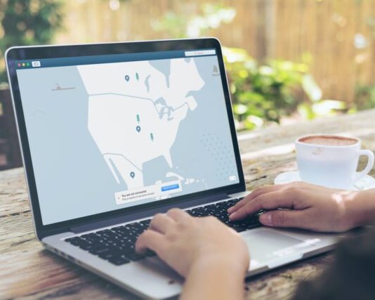 How to Set Up and Use a VPN for Beginners Person Using Black and Gray Laptop Computer Beside White Ceramic Cup on Brown Wooden Table