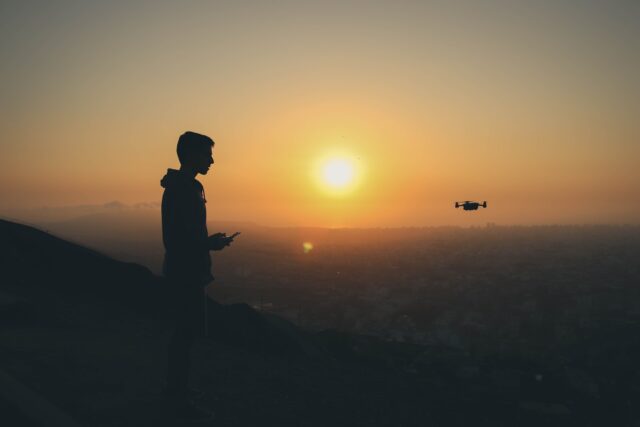 Photo by Nicolas Luna silhouette photo of man holding drone remote