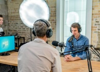 The Rise of Podcasts in Marketing: Harnessing Audio Content for Business Success man in gray shirt leaning on table with headphones facing another man leaning on table with headboard