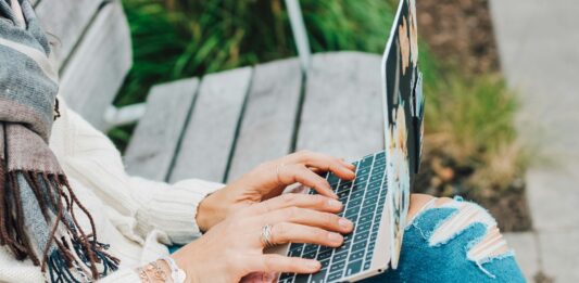 CooMeet – Omegle TV Alternative for Meeting New People person in white long sleeve shirt and blue denim jeans using macbook pro