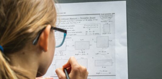 Tailoring Tests for Diverse Learning Needs in High Schools woman in black framed eyeglasses holding pen