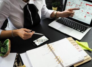 10 Benefits of Taking Real Estate Classes Today A business professional working on real estate project plans using multiple devices in an office setting.