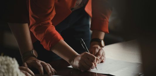 How Authentication Protects Canadian Nonprofits Operating Overseas person in orange long sleeve shirt writing on white paper