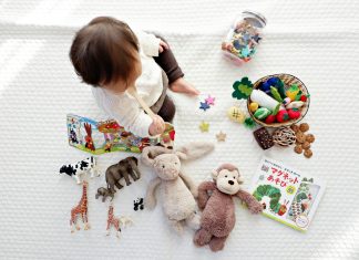 The Connection Between Play and Cognitive Growth boy sitting on white cloth surrounded by toys