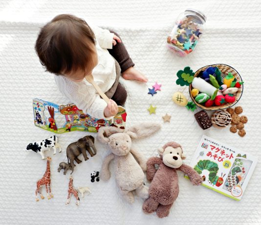 The Connection Between Play and Cognitive Growth boy sitting on white cloth surrounded by toys