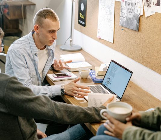 The Future of Online Master’s Education: Trends and Technologies Shaping the Way We Learn Young adults collaborating over laptops and notes during a study session indoors.