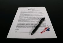 Short-Term Rental Licensing Reforms Across Jurisdictions Lease agreement document with pen and American flag keychain on a black table.