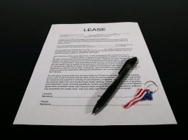 Short-Term Rental Licensing Reforms Across Jurisdictions Lease agreement document with pen and American flag keychain on a black table.