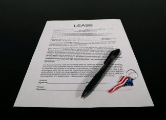 Short-Term Rental Licensing Reforms Across Jurisdictions Lease agreement document with pen and American flag keychain on a black table.