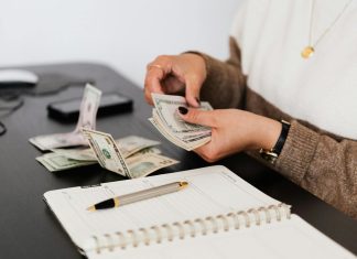 Common Budgeting Mistakes and How to Avoid Them Close-up of person counting cash with notepad on desk, indicating financial tasks.