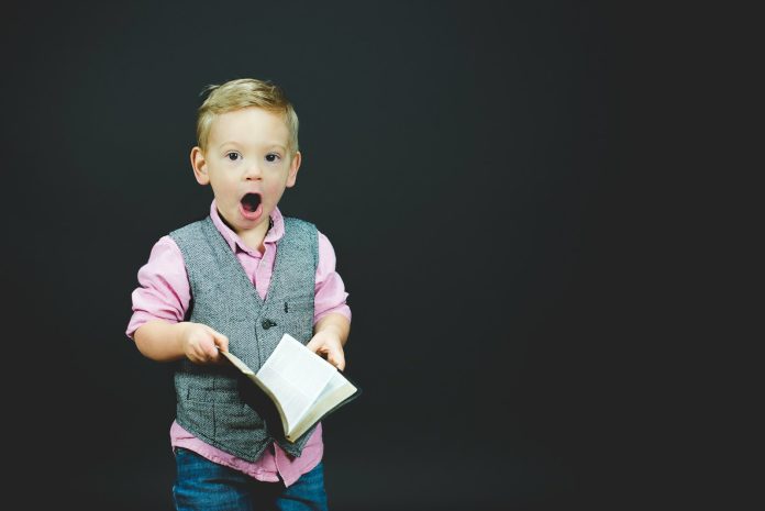 Photo by Ben White boy wearing gray vest and pink dress shirt holding book