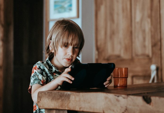 Photo by Annie Spratt selective focus of child using tablet computer on table